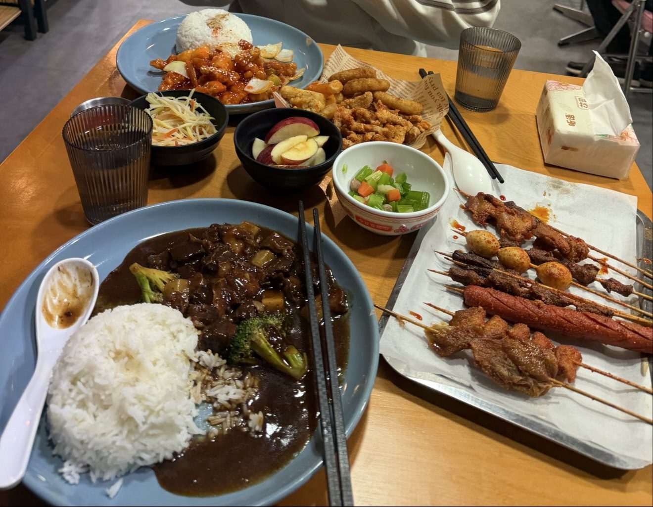 A shared table with rice, sides and assorted skewers at Bomb Fried Skewers